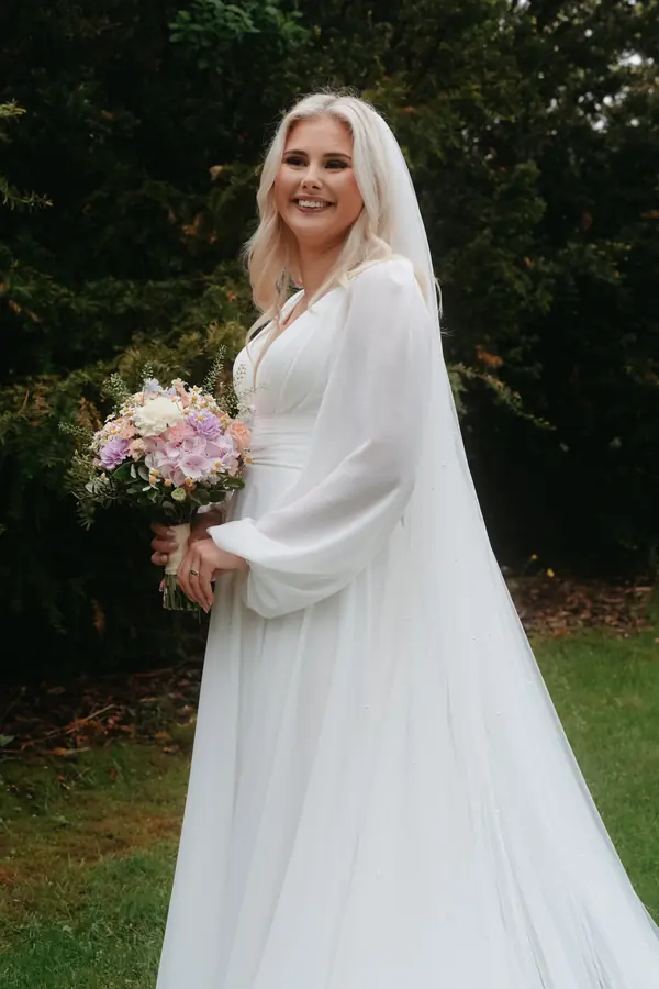 Brud med blomsterbukett i et utendørs portrett.