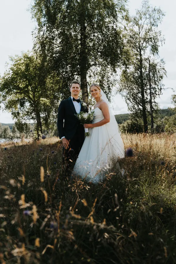 Brudepar står sammen i gyllent lys under et tre.