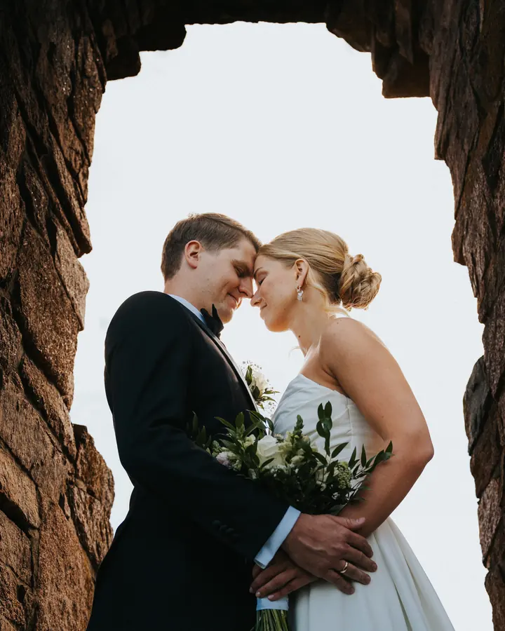 Brudepar kysser i åpningen av gamle steinruiner.